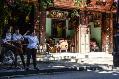 People sitting on street amidst buildings in city