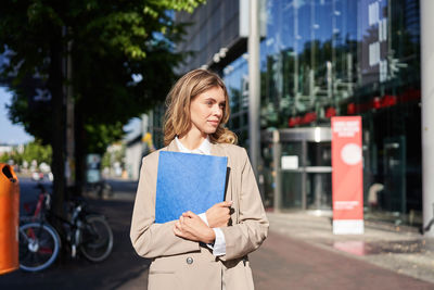 Portrait of young woman standing in city