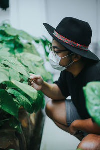 Young man wearing mask touching plant