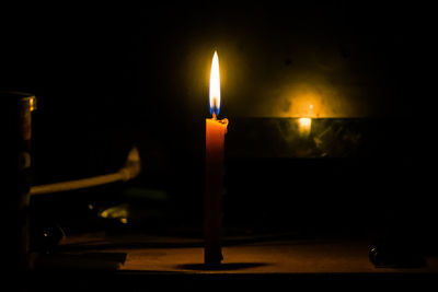 Close-up of lit candle in darkroom