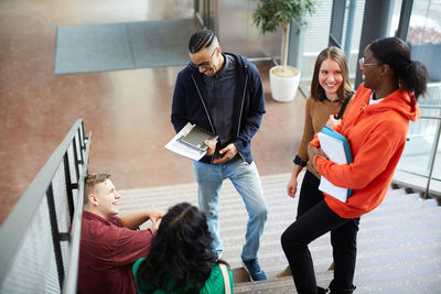 High angle view of male and female friends talking on steps in university