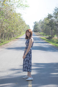 Portrait of smiling woman standing on road 