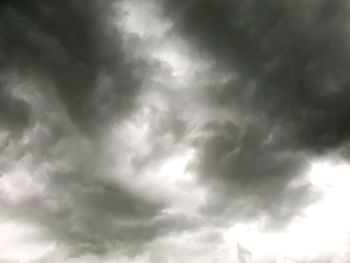 Low angle view of sunlight streaming through storm clouds