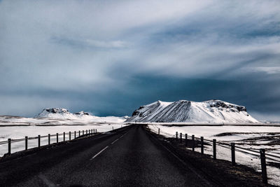 Road amidst snowcapped mountains against sky