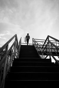 Low angle view of man standing on staircase against sky