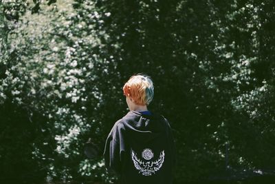 Rear view of young man standing against trees