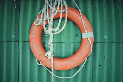 Life belt and rope hanging on green wall