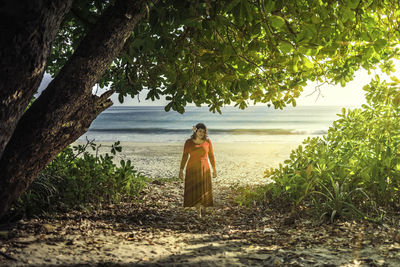 Woman standing by tree on beach