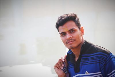 Portrait of young man sitting against wall