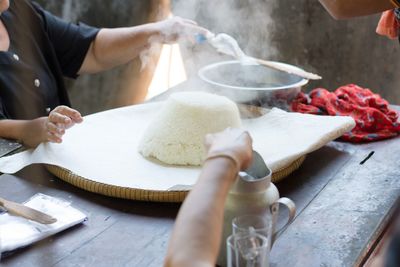 Midsection of people preparing food on table at kitchen