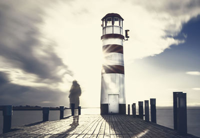 Rear view of man standing on pier against sky