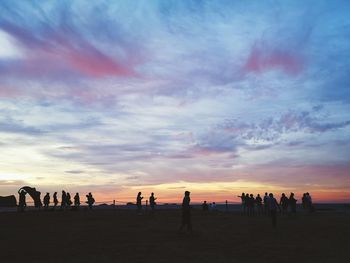 Silhouette people on beach against sky during sunset