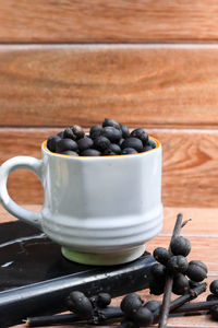 Black coffee beans in white cup with wooden background