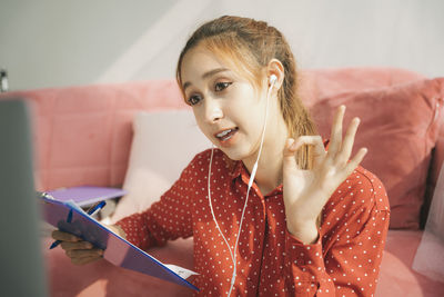 Portrait of young woman using phone while sitting on sofa at home