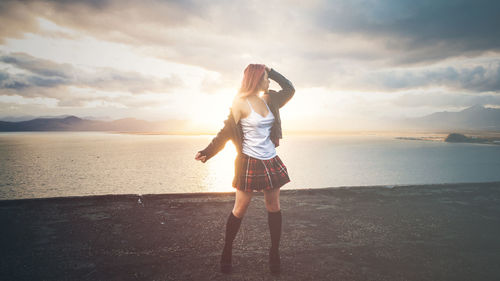 Rear view of woman standing on beach against sky