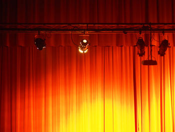 Illuminated stage light against orange curtain