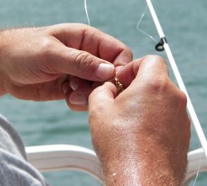 Cropped image of man holding fishing hook