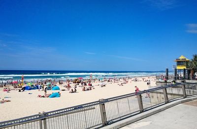 People enjoying at beach against blue sky