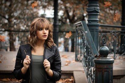 Young woman wearing jacket at public park during autumn