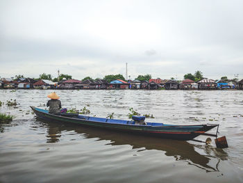 Man sitting on boat in river against sky