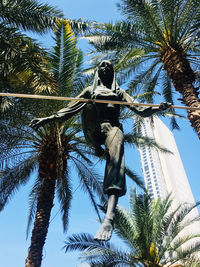 Low angle view of coconut palm tree against blue sky