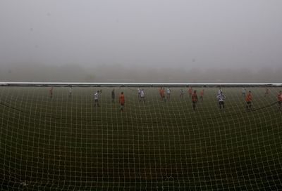 People on soccer field against sky
