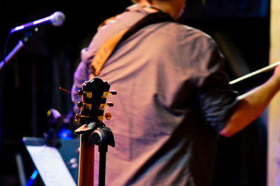 Close-up of guitar against musician performing on stage at nightclub