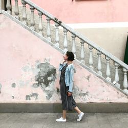 Woman standing on staircase against wall