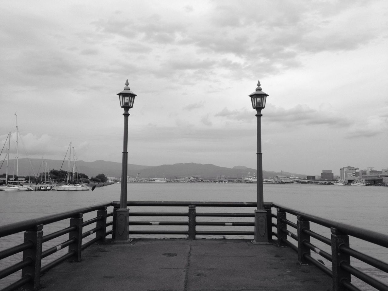 sky, water, street light, cloud - sky, railing, built structure, sea, architecture, building exterior, lighting equipment, city, river, cloudy, tower, cloud, transportation, travel destinations, nature, lamp post, harbor