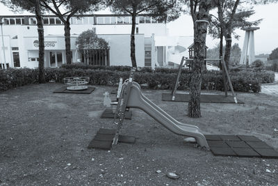 Empty bench in park against buildings in city