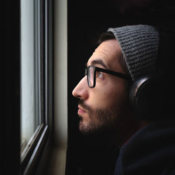 Close-up of young man looking through window