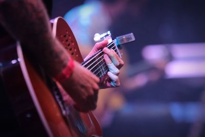 Midsection of man playing guitar