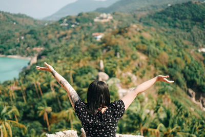 Rear view of woman with arms outstretched standing on mountain