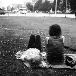 Friends relaxing on field in public park