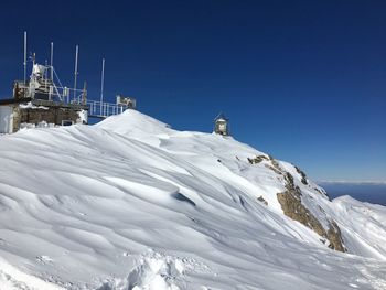 Low angle view of snowcapped mountain against clear blue sky