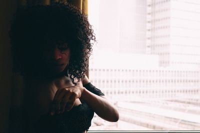 Woman with curly hair standing by window