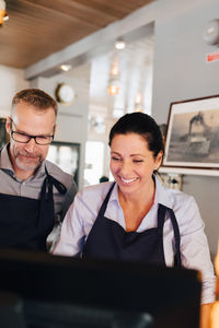 Smiling owners using computer in restaurant