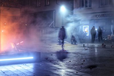 People walking on illuminated street at night