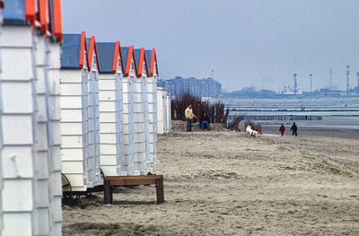 Hooded beach chairs on sand against buildings in city