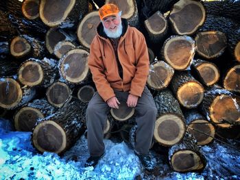 Portrait of man siting on stack of firewood