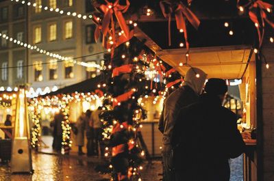 Rear view of people on illuminated street at night