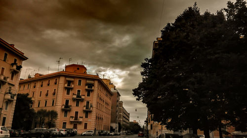 Low angle view of trees against cloudy sky