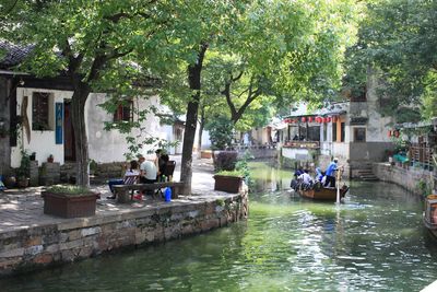 People on boats in canal along trees