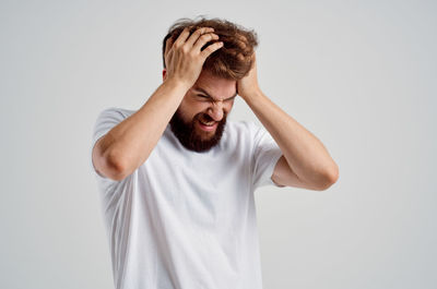 Portrait of young man standing against white background