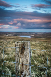 Wooden fence on field against sky