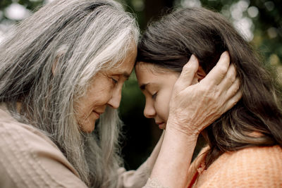 Side view of grandmother and granddaughter touching heads with eyes closed