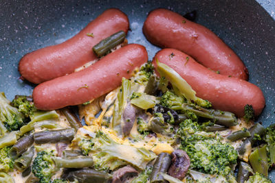 Fried sausages and vegetables with mushrooms and chicken egg on skillet