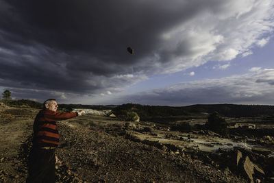 Senior man throwing stone on field