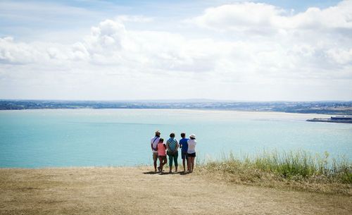 Friends standing on beach against sky