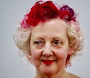 Close-up of thoughtful mature woman with dyed hair against white background